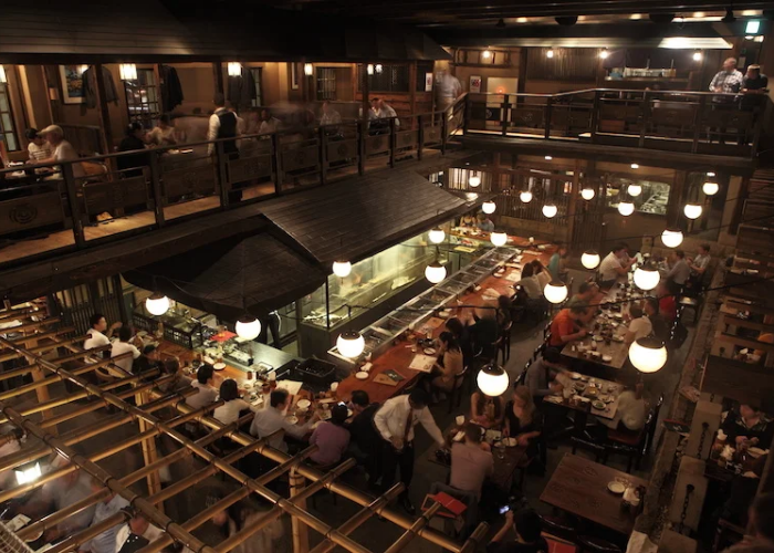 An interior shot of Gonpachi Nishiazabu, known more famously as the Kill Bill restaurant in Tokyo. It is filled with people dining across two levels.